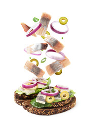 Tasty bruschettas with herring and flying ingredients on white background