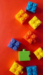 Naklejka premium Brightly colored toy building blocks arranged on red background, playtime, educational