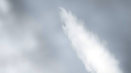 A vibrant water jet ascends into the expansive blue sky, a contrast against the airy cloudscape