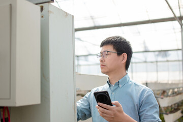 An Asian male farmer and the electrical box in the greenhouse