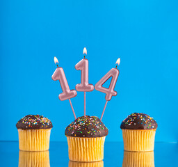Three birthday cupcakes with number 114 candle - Blue background