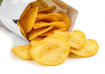 A bag of golden potato chips spilling out onto a white surface in a close up studio shot view image