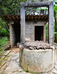 A traditional village bathroom setup featuring a manual well and two separate rooms. one for bathing and the other for toilet use