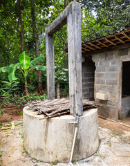 A traditional village bathroom setup featuring a manual well and two separate rooms. one for bathing and the other for toilet use