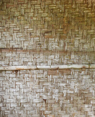 A close-up view of a traditional woven bamboo wall, showcasing the intricate craftsmanship and natural texture of each interlaced strip