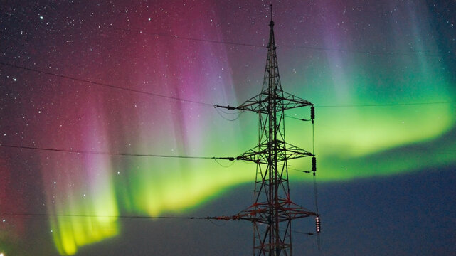 Northern Lights Illuminate the Sky Beyond an Electrical Transmission Tower - Powered by Adobe