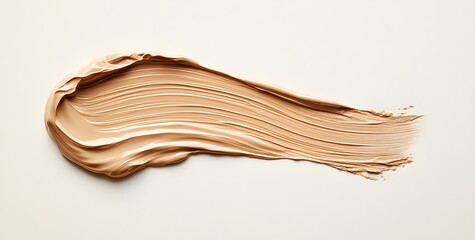 Brush stroke of liquid foundation on a white background, with the skin tone being a natural and radiant beige color,