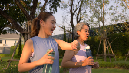 Young adult child workout outdoor public park run walk hold water bottle with mature middle age old...