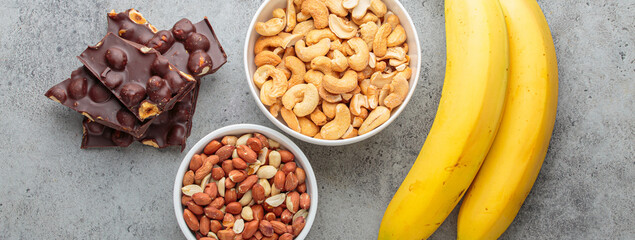Assortment of food rich in a magnesium: cashews, peanuts, bananas, and chocolate hazelnuts, a...