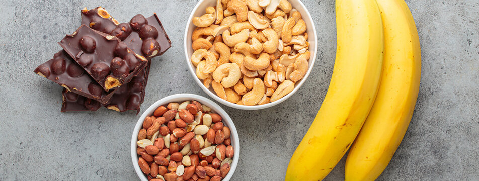 Assortment of food rich in a magnesium: cashews, peanuts, bananas, and chocolate hazelnuts, a healthy snack for mood and brain boost