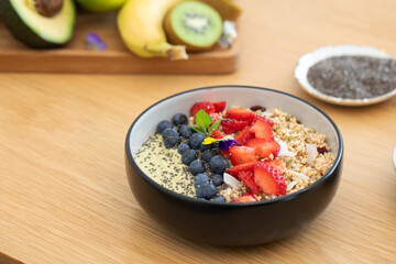 Healthy breakfast avocado smoothie bowl with fresh fruits and chia seeds on wooden table