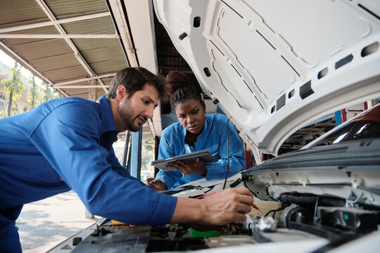 EV car check, mechanic workers coworker inspects and maintains service of electric engine and battery in fixed automobile garage station, professional technology transportation industry business.