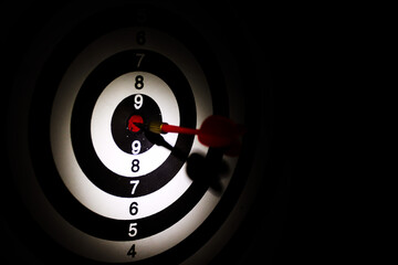 Dart arrow hitting in the target center of dartboard,Arrow on a black background