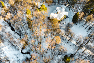 A panoramic view of a vibrant winter scene, featuring a river and a cottage nestled amidst the woods. Turliki Manor, Obninsk, Russia