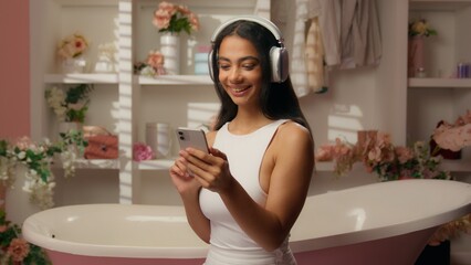 Hispanic Latina girl happy cheerful carefree woman listen music in pink candy bathroom relaxed teenager female in headphones fun relax dance sound phone audio musical dancing healthy self-care beauty