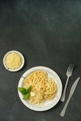 Simple pasta and cheese plate on dark textured surface.