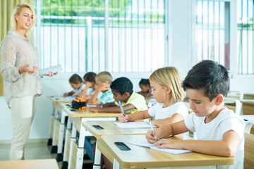 School children writing test, smart young people studying at primary school