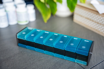 Weekly pill organizer with labeled compartments for daily medication doses. Concept of health management and medication planning