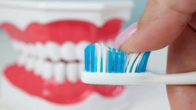 Close-up of a woman's finger running over the bristles of a toothbrush