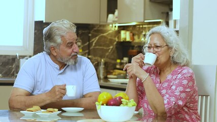 Happy retired senior indian couple enjoy morning tea together at home, Romantic mature husband wife drink coffee at table and having conversation, Love and bonding. Retirement life and insurance, 4k - Powered by Adobe
