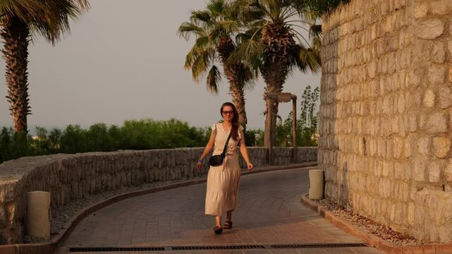 A woman joyfully walking through a stunning landscape, surrounded by vibrant palm trees