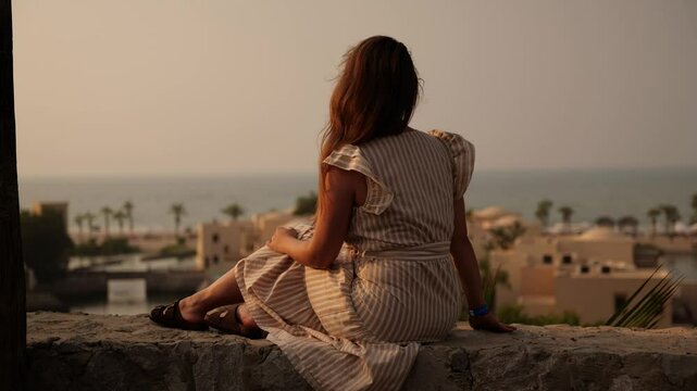 A Woman Enjoying a Stunning Scenic View by the Sea During a Beautiful Sunset Experience