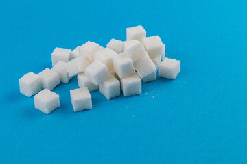 Sugar cubes scattered on a solid blue background creating a visual contrast