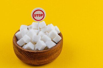 Bowl filled with sugar cubes and a stop sign on a bright yellow background