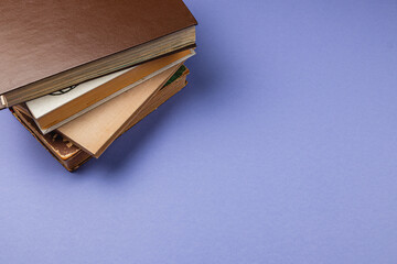 Stack of vintage books resting on a light purple surface