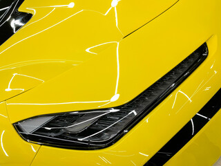 Charging an yellow electric car with a connected power cable close-up.  The concept of ecological...