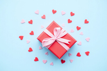 red gift box with a red ribbon and hearts on a blue background