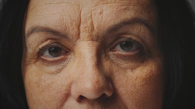 close-up eyes sad sight senior elderly woman looking at camera. lady old age skin with deep wrinkles. depressive mood, unhappy woman, brown eye, part of face cut off, unrecognizable silhouette