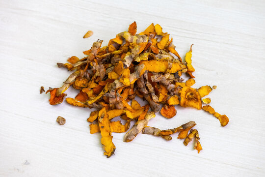 Raw turmeric skins, piled on a light wooden surface, offer benefits such as skin brightening, spot reduction, and natural exfoliation. They are also suitable for composting and soil fertilization.