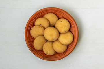 Top view of delicious, salty cookies (biscuits) on a clay plate, set against a wooden background. Their buttery goodness will leave you craving more.
