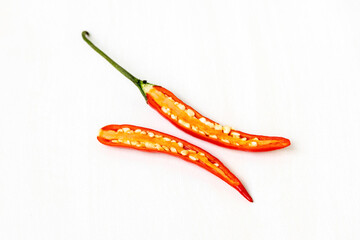 A fresh, ripe red chili, cut in half to reveal its inner texture and seeds, is isolated on white....