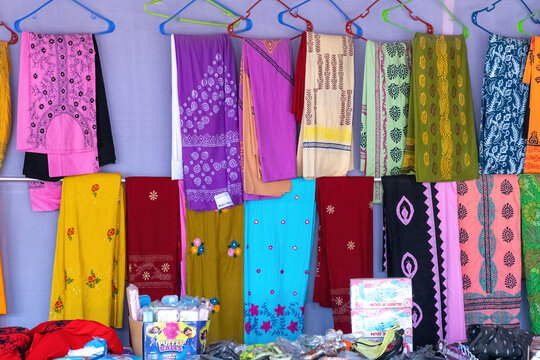 Colorful three-piece cotton textile clothes for women displayed on hangers for tourist sale at the international trade fair, Kishoreganj. Beautiful tunics and salwar kameez fabrics.