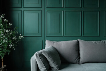A living room with a gray sofa, deep green paneled accent wall background and decoration