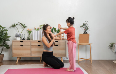 Connection and Exercise. A mother and daughter share laughter and support during a playful yoga...