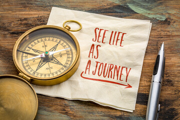 See life as a journey  - inspirational writing on a napkin with an antique brass compass