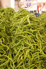 Fresh green chilies stacked at local market in bustling city