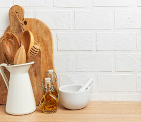Kitchen utensils resting on wooden countertop with white brick wall background