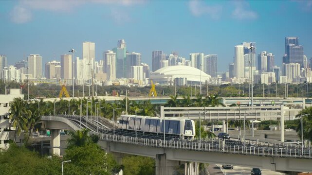 Downtown Miami, Florida, USA - MARCH 5, 2025: View of downtown Miami skyline with modern skyscrapers in the background. A metro train passes on an elevated track in the foreground above a highway.