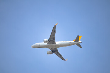 Yellow tail passenger plane flying in blue sky. Aviation idea concept. Aircraft. Travel abroad. Airlines. Copy space, blank, empty. 