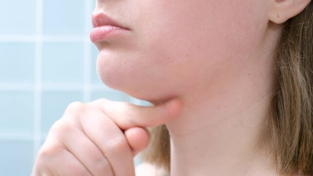 Female face with double chin close-up on blue background, side view.
