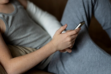 A child with an arm in a cast uses a phone