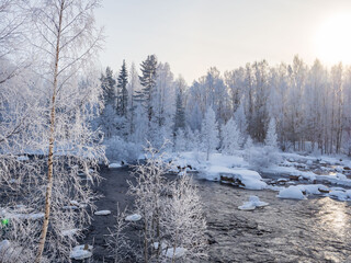 Winter landscape in the Republic of Karelia, northwest Russia: snow, frost, hoarfrost on trees, steam over the river. Very severe frost