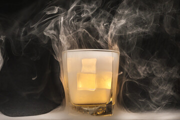 Opaque transparent ice filled drink short glass yellow tungsten light flame smoke fog on black...