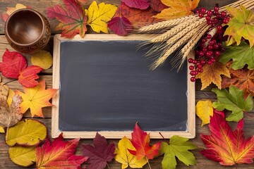 A photo of a rustic wooden table covered with an array of autumn leaves