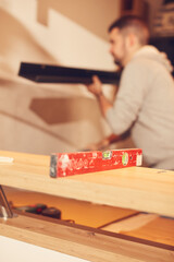 Handyman mounting new kitchen cabinets and shelf.