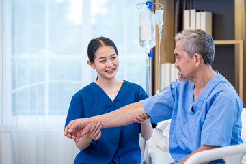 Senior Asian man patient get medical service visit from caregiver nurse at hospital while doing physical therapy to shoulder stretching for muscle pain in health care and pension welfare